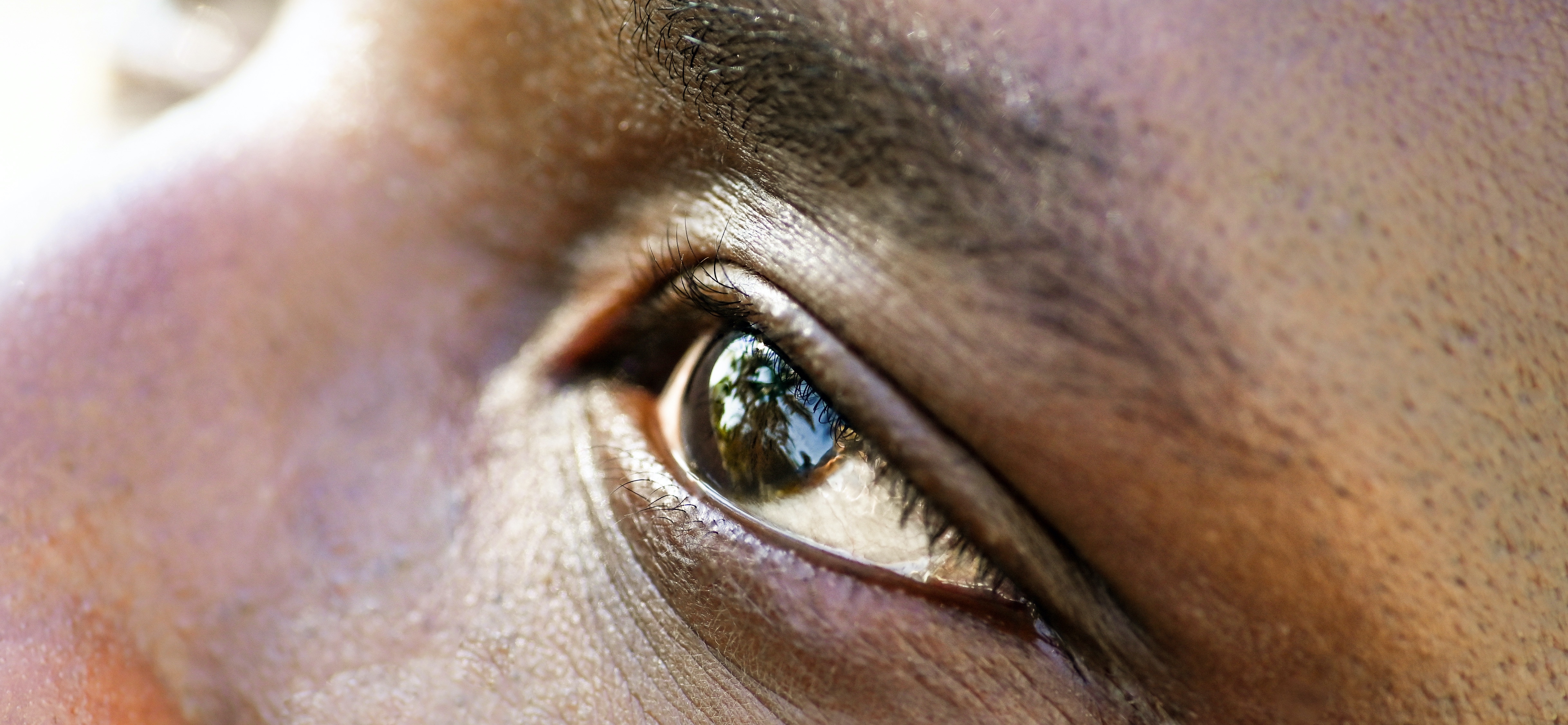 close-up of man's face, focusing on his eye, as he looks upward