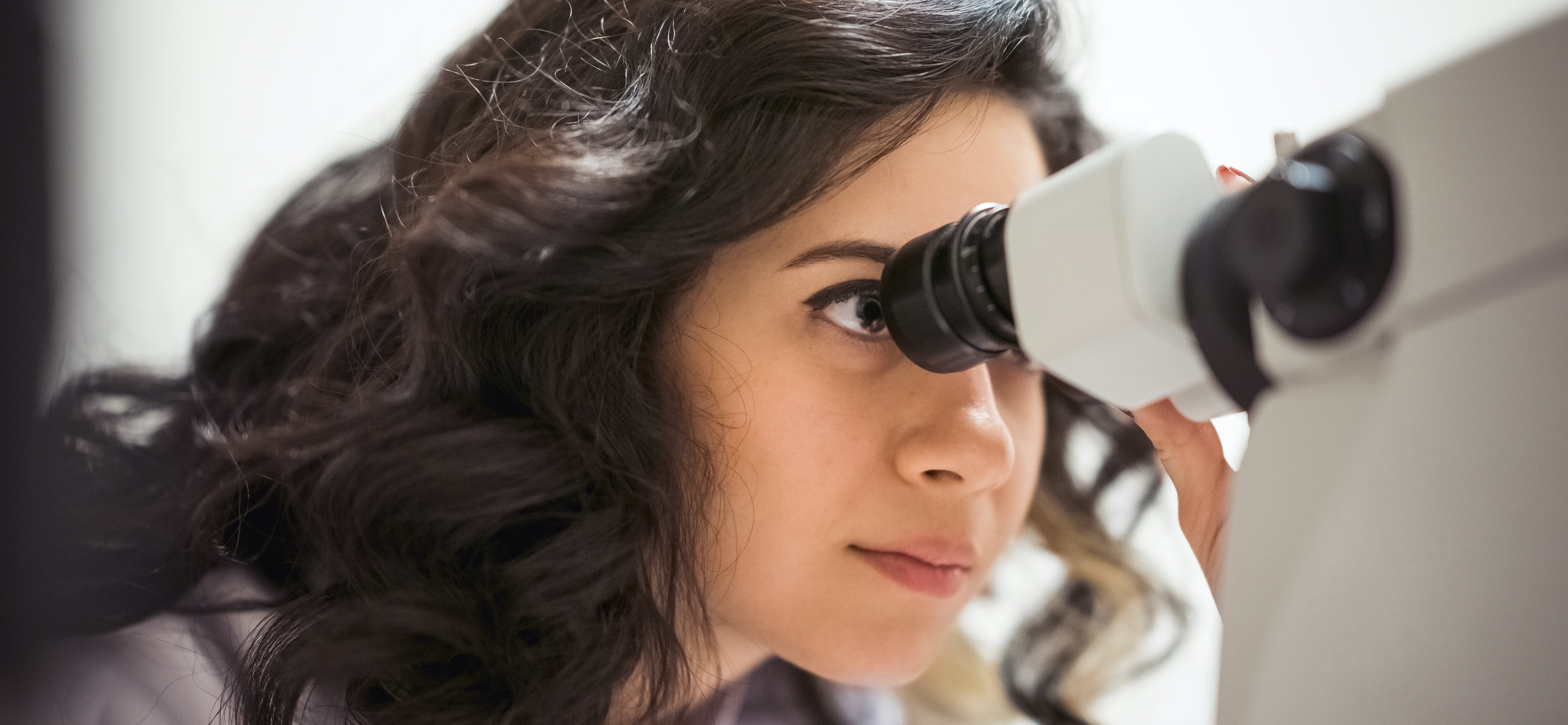 Young woman, looking into microscope